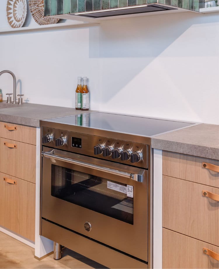 Bertazzoni inductie fornuis RVS 90 cm 1 oven in een moderne houten keuken met groene tegel schouw