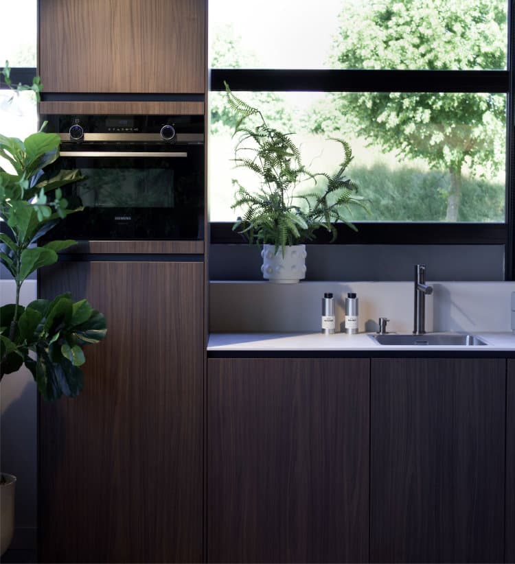 Modern industriële keuken greeploos walnoot, betonlook wit werkblad en smetplint, RVS kraan en spoelbak en zwart Siemens combi-oven